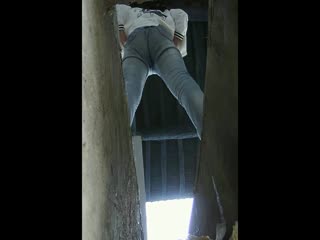 A close-up sneak shot of a white and tender big ass beauty in a simple rural toilet with a leucorrhea hanging on her neck, about to touch the dirt below